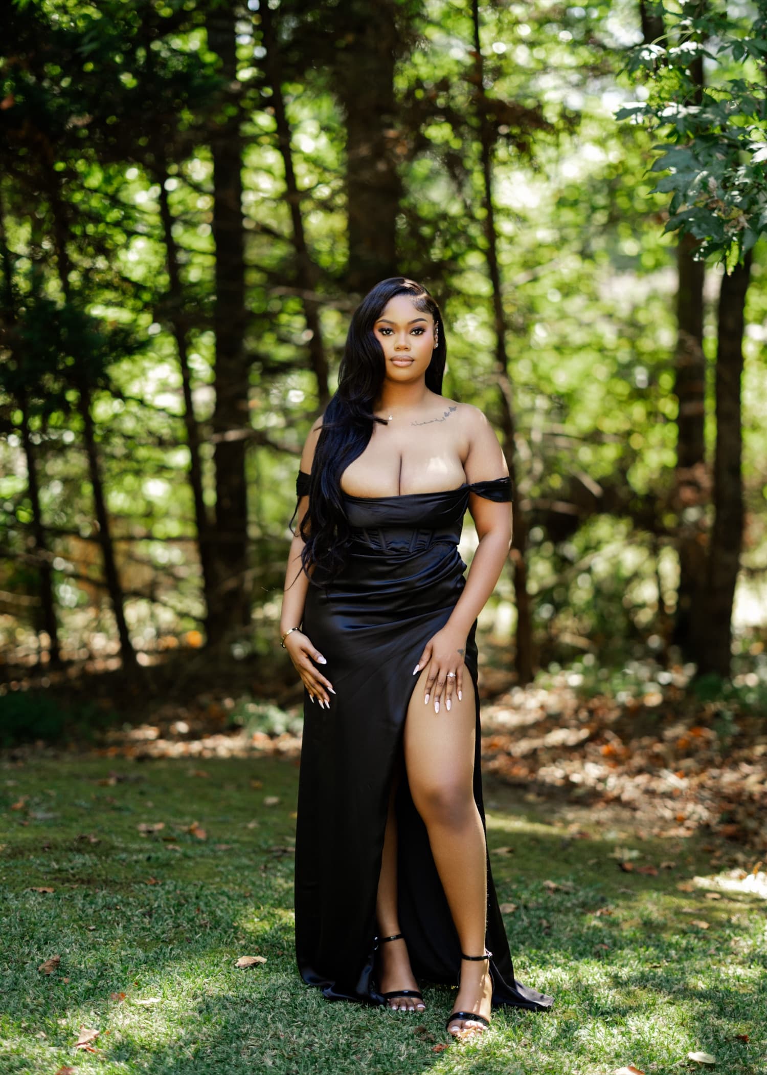 A portrait in a black off-shoulder gown against sunlit woodland